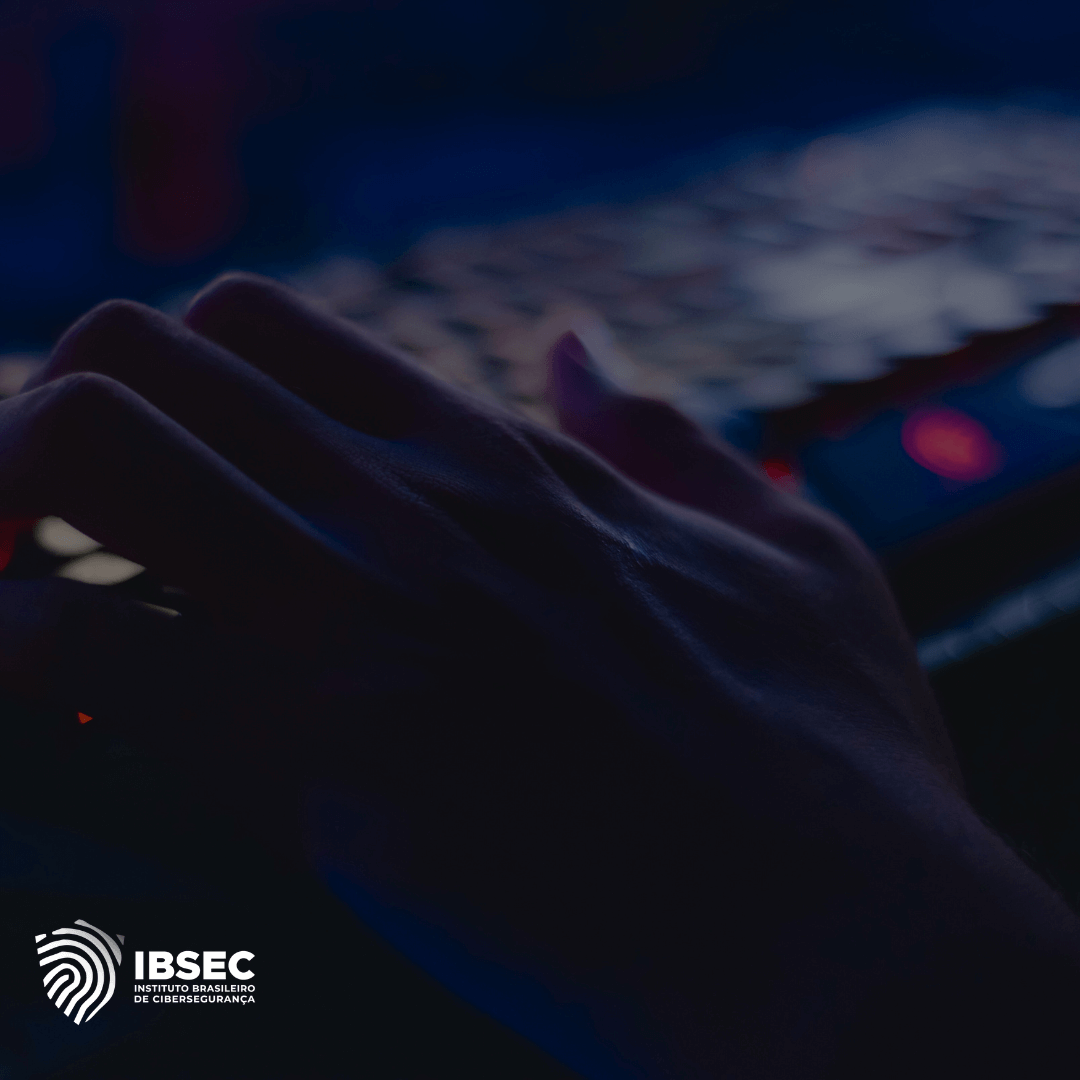 Uma mão digitando em um teclado de computador iluminado em um ambiente escuro, com o logotipo do IBSEC (Instituto Brasileiro de Cibersegurança) no canto inferior esquerdo da imagem.