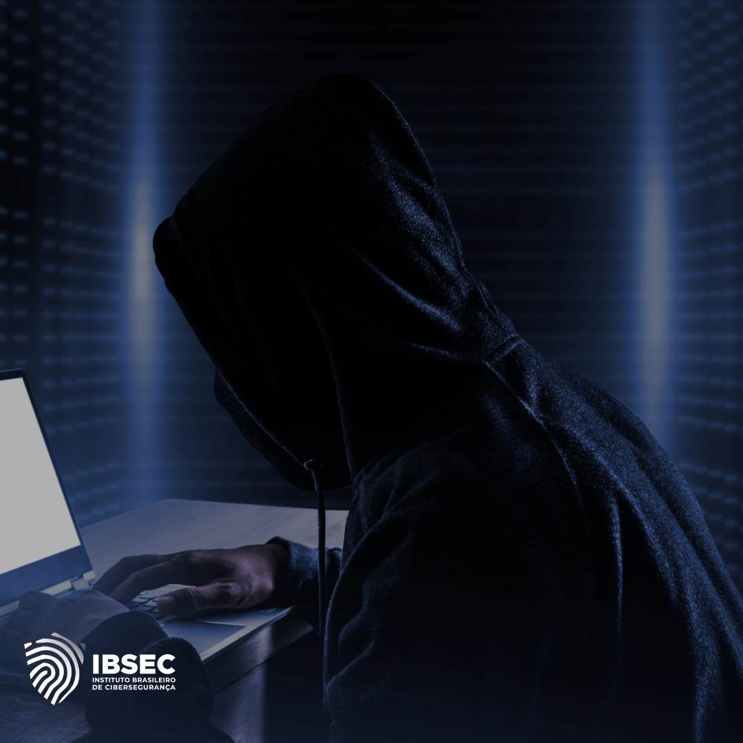 Imagem de um hacker de capuz preto, sentado em frente a um laptop em um ambiente escuro, simbolizando uma ameaça cibernética. O logo do IBSEC - Instituto Brasileiro de Cibersegurança - está localizado no canto inferior esquerdo.