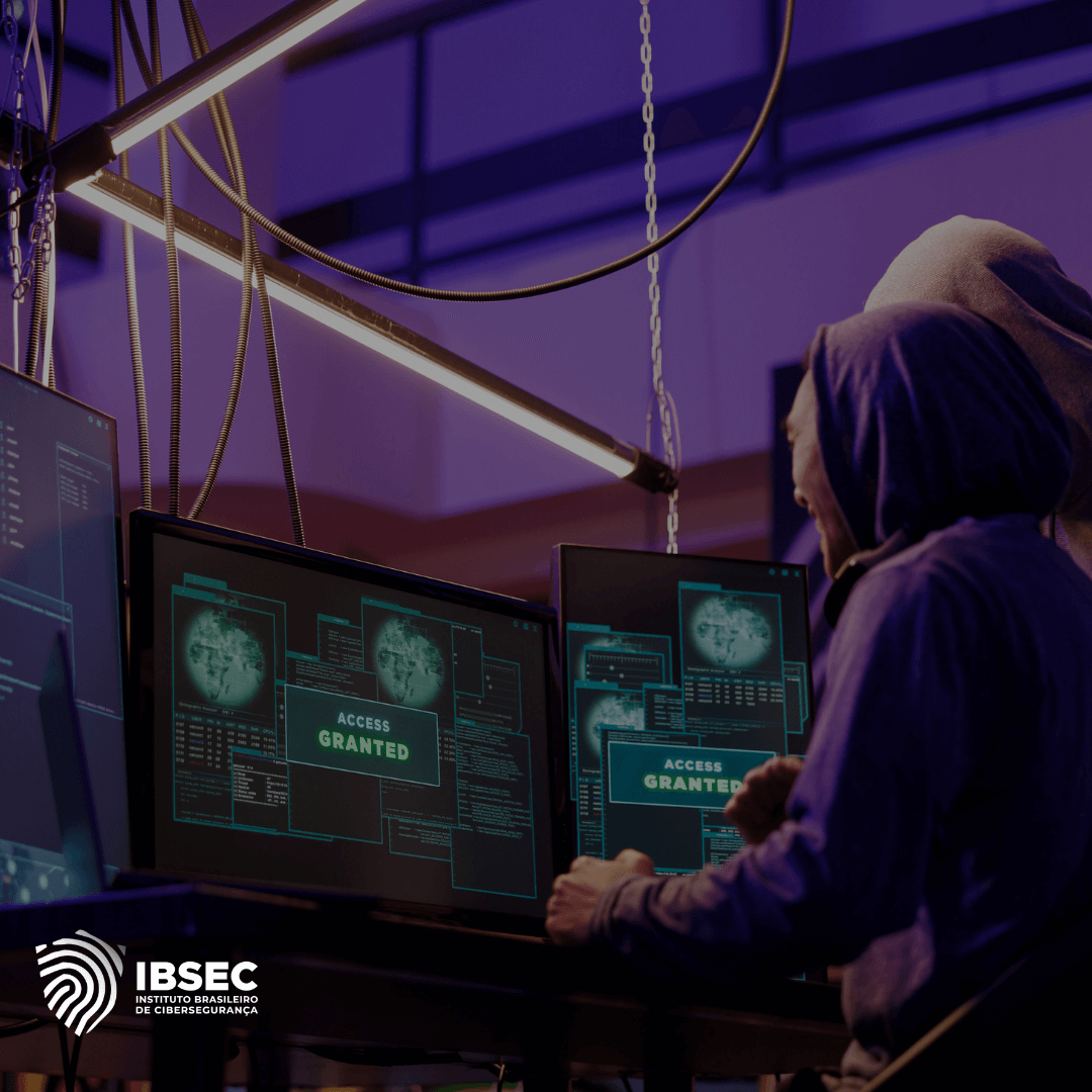 Imagem mostrando duas pessoas com capuzes, trabalhando em um ambiente de cibersegurança com vários monitores exibindo a mensagem "Access Granted". A cena está iluminada por uma luz fria, destacando a atividade de invasão digital ou teste de segurança cibernética. No canto inferior esquerdo, está o logotipo do Instituto Brasileiro de Cibersegurança (IBSEC).