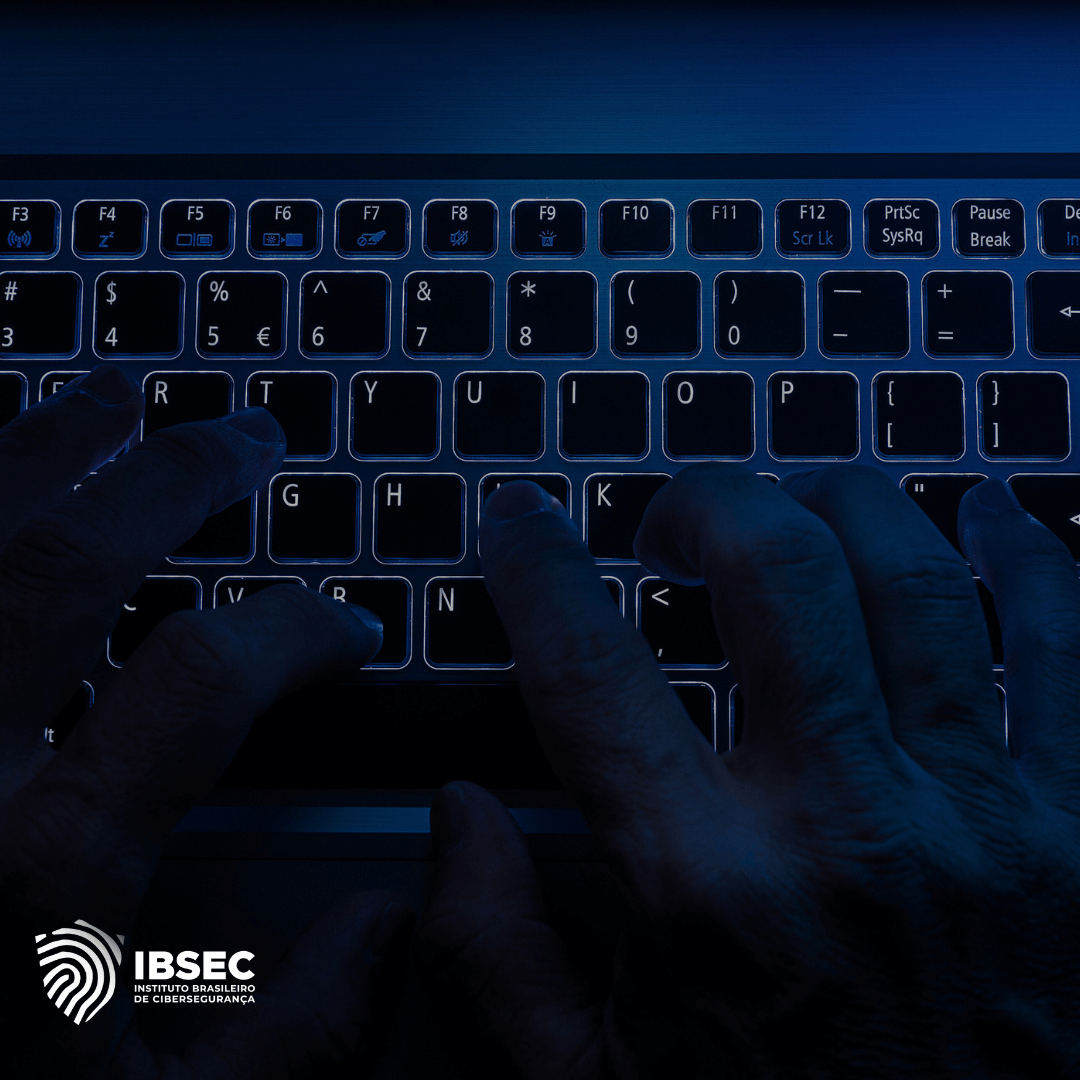 Mãos digitando em um teclado iluminado, em ambiente escuro, destacando a ação de digitação. No canto inferior esquerdo, o logo do IBSEC - Instituto Brasileiro de Cibersegurança.