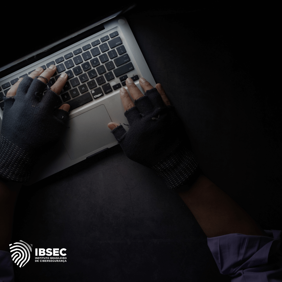 A imagem mostra um indivíduo digitando em um teclado de laptop, usando luvas sem dedos, o que sugere atividades secretas ou cibernéticas, como hacking. O fundo escuro e o enquadramento destacam as mãos, criando uma atmosfera de sigilo ou potencial ameaça cibernética. No canto inferior esquerdo, está o logotipo do IBSEC (Instituto Brasileiro de Cibersegurança), reforçando o tema de cibersegurança e proteção digital.