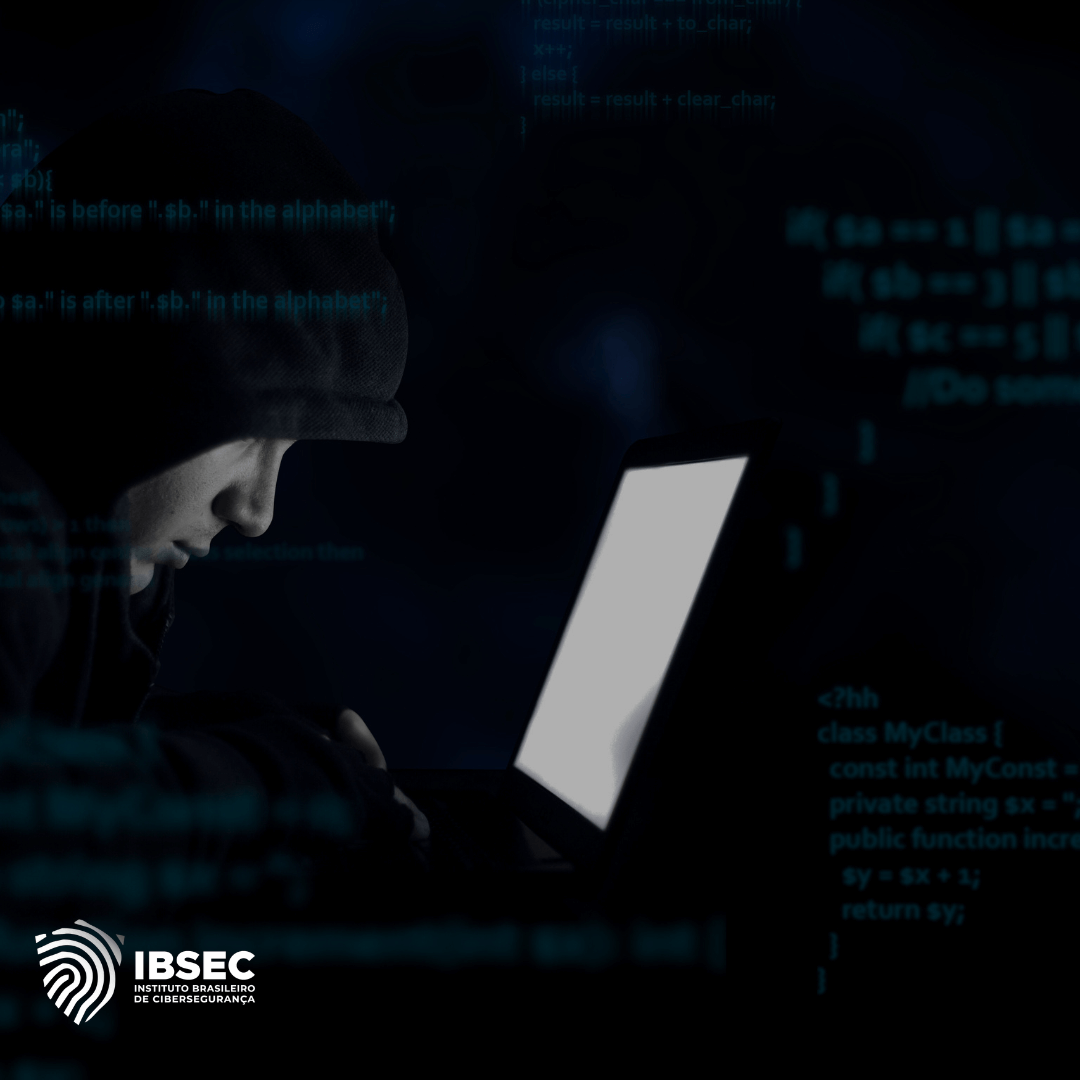 Imagem de uma pessoa usando capuz em frente a um laptop, em um ambiente escuro, com linhas de código no fundo. A imagem representa um cenário de ameaça cibernética ou ataque hacker. No canto inferior esquerdo, há o logotipo do IBSEC (Instituto Brasileiro de Cibersegurança).